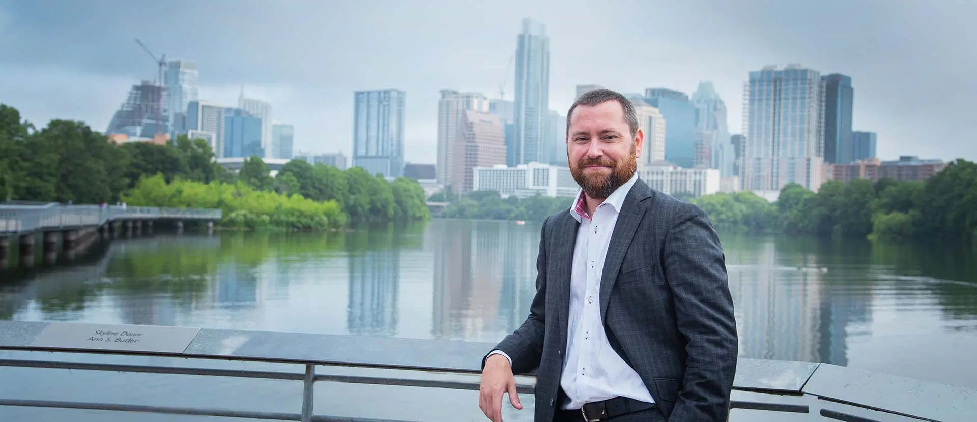 Attorney Todd A. Wilson on the boardwalk at Lady Bird Lake with the Austin skyline behind him